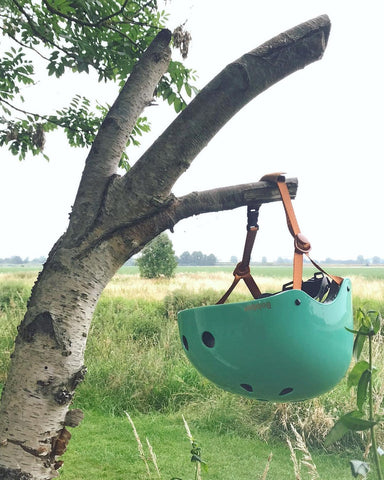 green bobbin helmet hanging on a tree branch