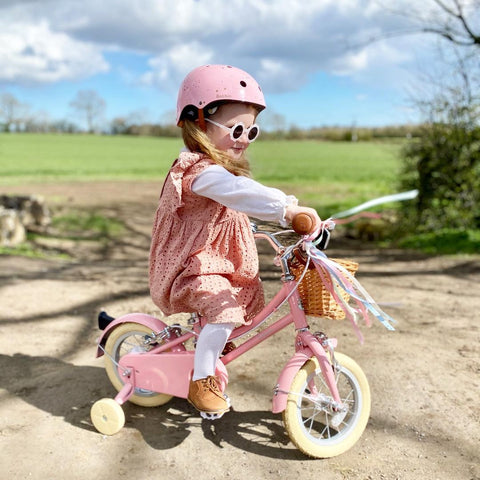 coordinated pink helmet clothes and bike with stabilisers
