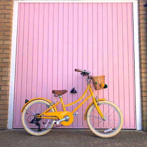 yellow bike with basket and pom pom garland