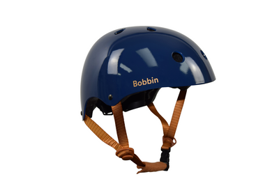 This image shows a close-up of a blue kids bike helmet. The bike helmet has the name Bobbin written on it. The colours in the image include shades of blue, white, and brown. The Kids helmet is the main focus of the image, with no other objects present. The helmet appears to be in good condition and is clean. The name "Bobbin" is prominently displayed on the front of the helmet. Overall, this image captures a detailed view of a personalized blue bicycle helmet and the name Bobbin on it.