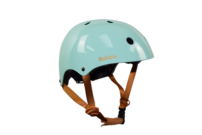 This image shows a close-up of a Green kids bike helmet. The bike helmet has the name Bobbin written on it. The colours in the image include shades of Green, white, and brown. The Kids helmet is the main focus of the image, with no other objects present. The cycle helmet appears to be in good condition and is clean. The name Bobbin is prominently displayed on the front of the kids helmet. Overall, this image captures a detailed view of a personalised Pink toddler helmet and the name Bobbin on it.